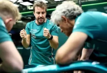 Fernando Alonso in Aston Martin team kit talking with engineers alongside the car