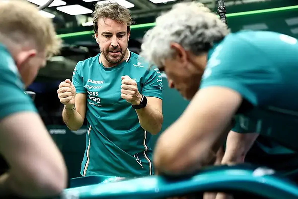 Fernando Alonso in Aston Martin team kit talking with engineers alongside the car