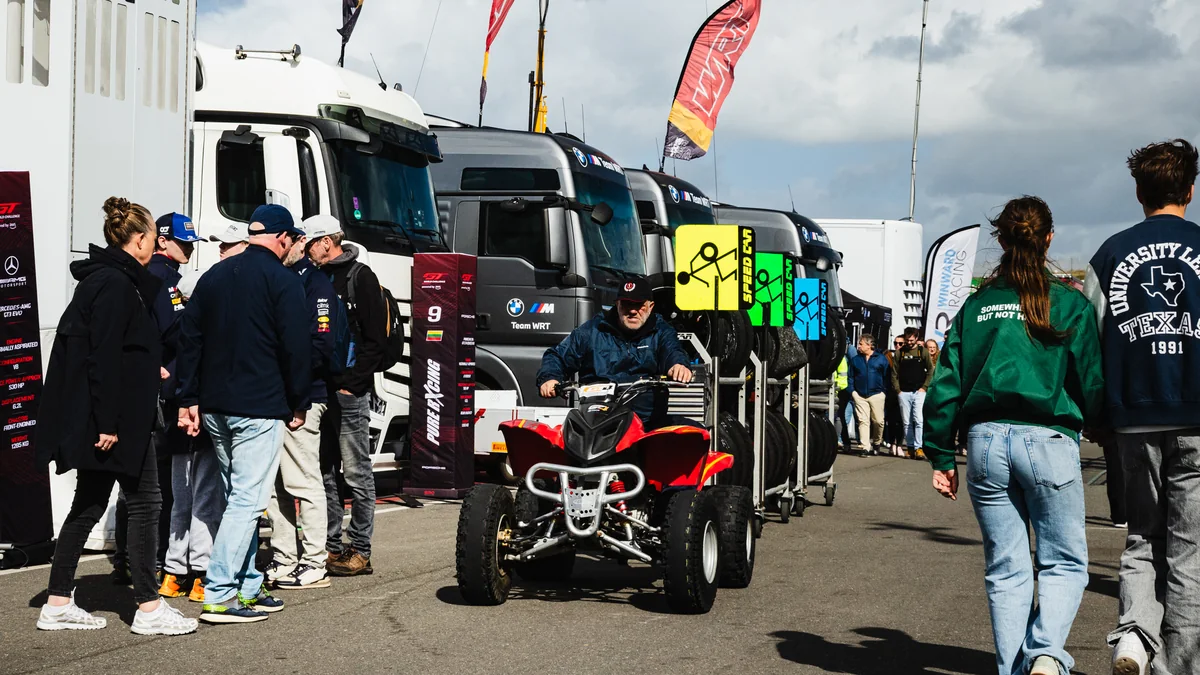 Spectators walking between team transporters in the open paddock at Circuit Zandvoort