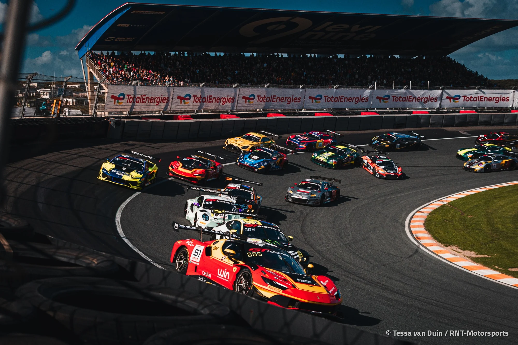 The GT World Challenge field three wide through the banked Hugenholtzbocht on the first lap of Race 2 at Zandvoort