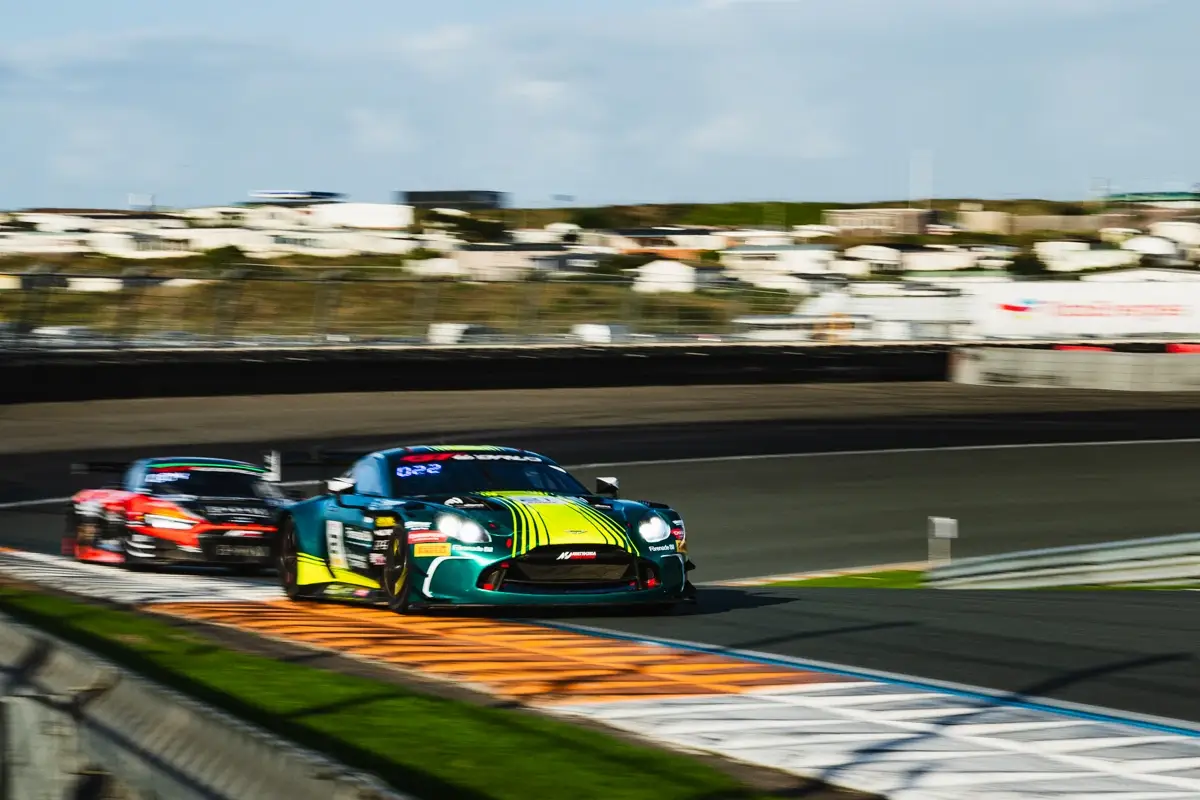 A green and yellow Aston Martin Vantage GT3 ahead of a red GT3 car at Zandvoort