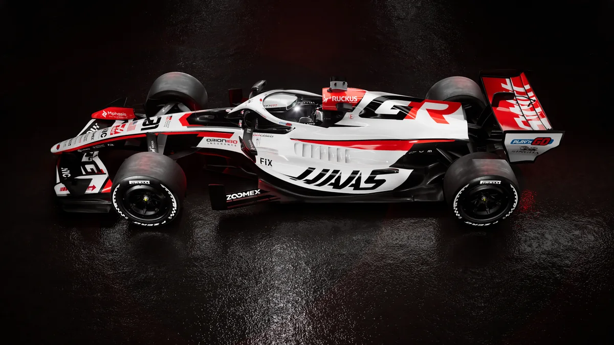 The Haas VF26 in its 2026 launch livery photographed from the side in a dark studio