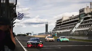 The red and black number 77 Schubert Motorsport BMW M4 GT3 EVO crosses the finish line under the chequered flag at the Nurburgring