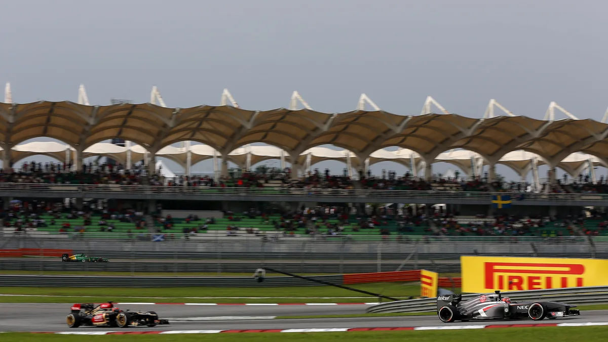 A Lotus and a Sauber in front of the grandstand at Sepang during the 2013 Malaysian Grand Prix