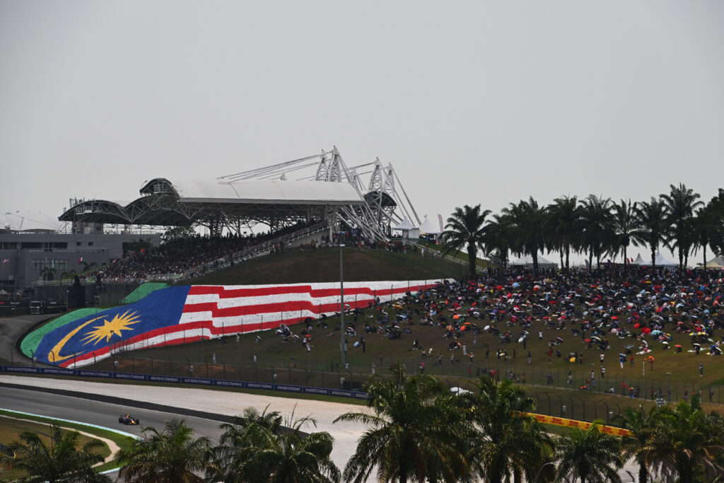 Isack Hadjar's Red Bull passes the main grandstand with the Malaysian flag at Sepang during final practice