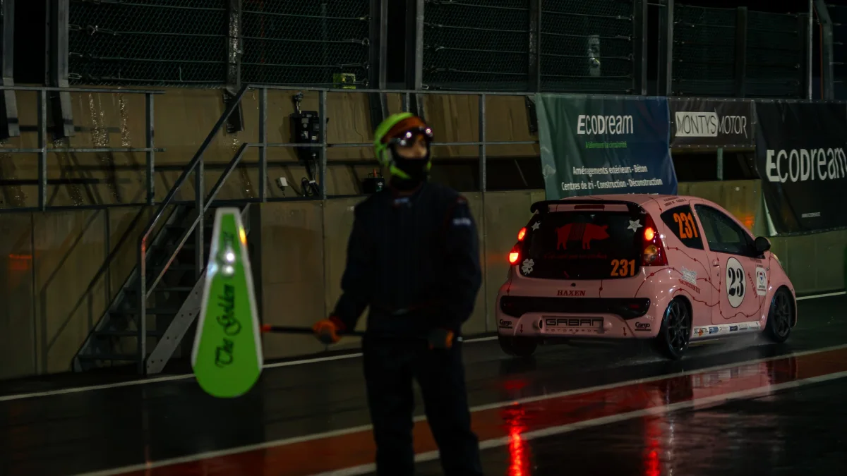 The pink #231 Gaban Motorsport Citroen C1 in the pit lane at night with a marshal in front