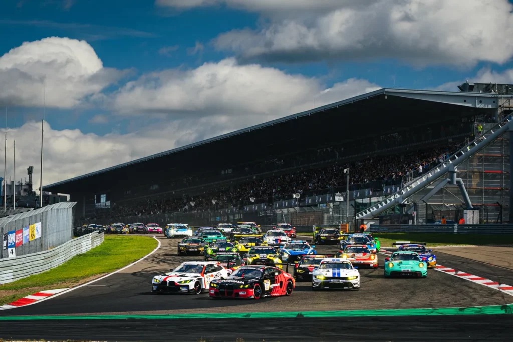 The NLS8 GT3 field led by the number 77 Schubert BMW and number 23 Gamota BMW into turn one in front of a full grandstand at the Nurburgring
