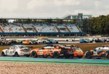 Supercar Challenge field with a white BMW M2 and an orange BMW M4 in front of the grandstand at TT Circuit Assen