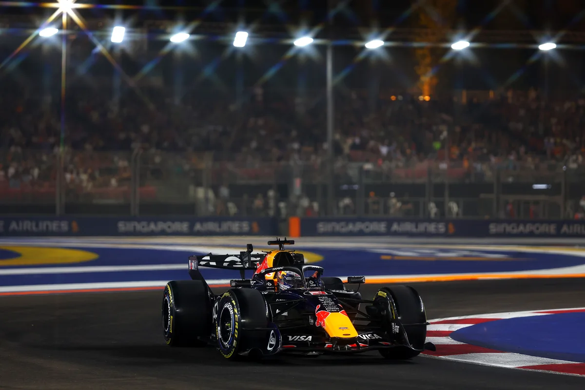Max Verstappen in the Red Bull RB22 at Marina Bay Street Circuit during Sprint Qualifying, with floodlights behind the grandstand