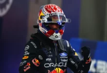 Max Verstappen in his helmet celebrates pole position in parc ferme after qualifying for the 2026 Singapore Grand Prix