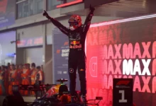 Max Verstappen stands on his Red Bull in parc ferme with arms raised after winning the 2026 Singapore Grand Prix