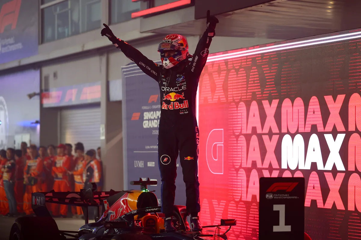 Max Verstappen stands on his Red Bull RB22 in parc ferme with arms raised after winning the 2026 Singapore Grand Prix