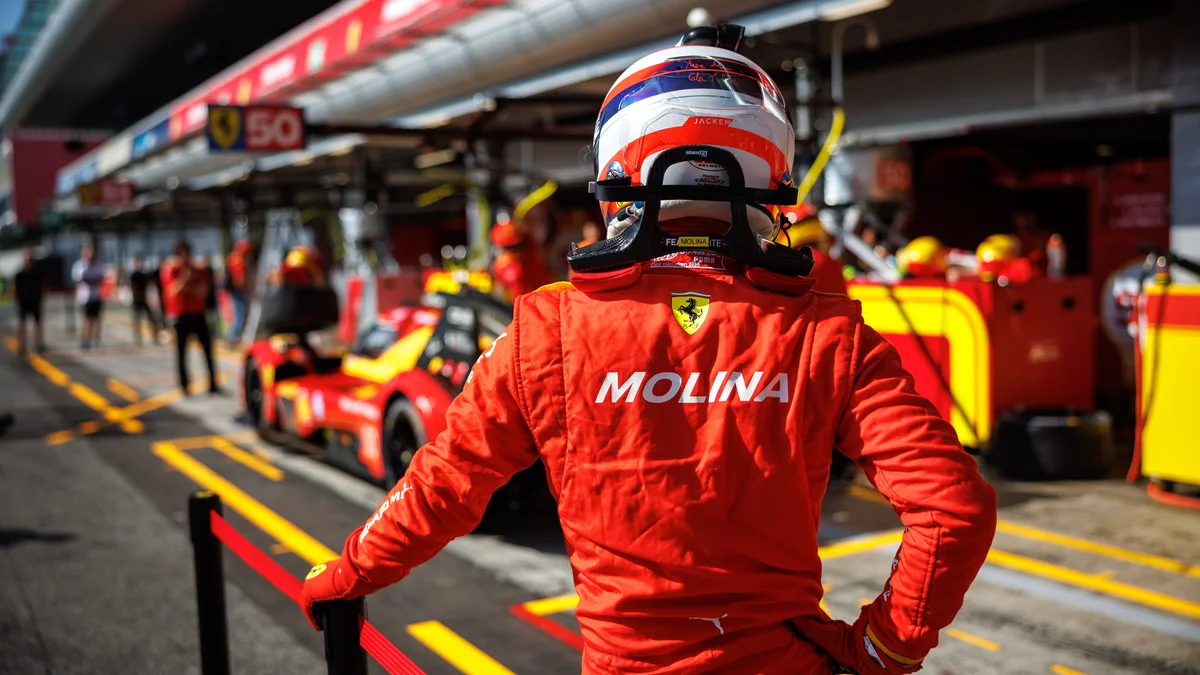 Miguel Molina in his Ferrari race suit in the pit lane, with a Ferrari 499P behind him