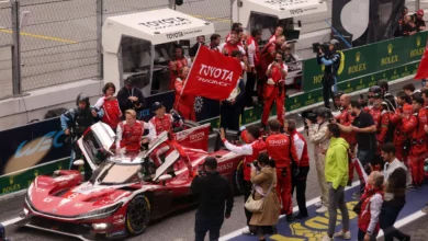 The #8 Toyota crew celebrates victory in the Barcelona pit lane as a team member waves a Toyota Racing flag