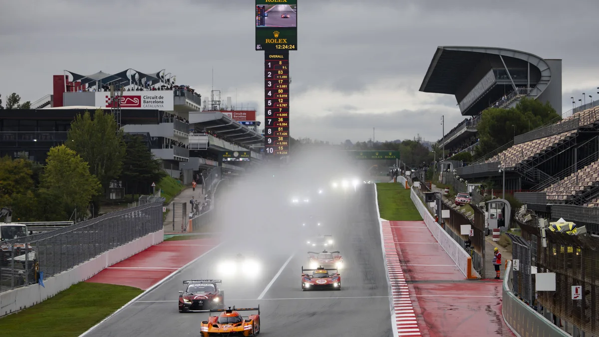 The orange #17 Genesis leads cars through the spray on a wet Circuit de Barcelona-Catalunya main straight