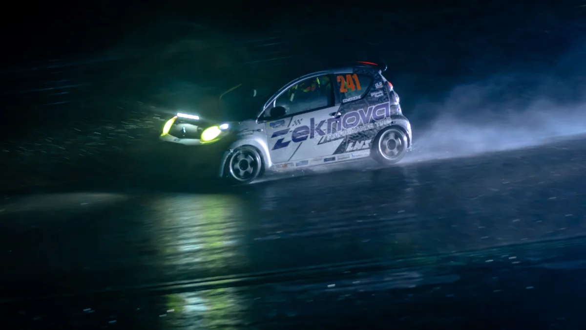 The #241 Zeknova Citroen C1 throwing up spray on a wet track at night